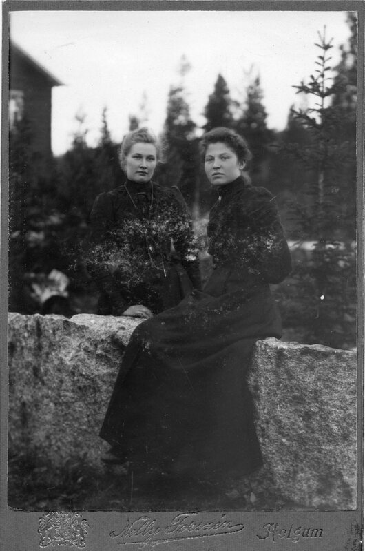 Två okända kvinnor vid en stenmur