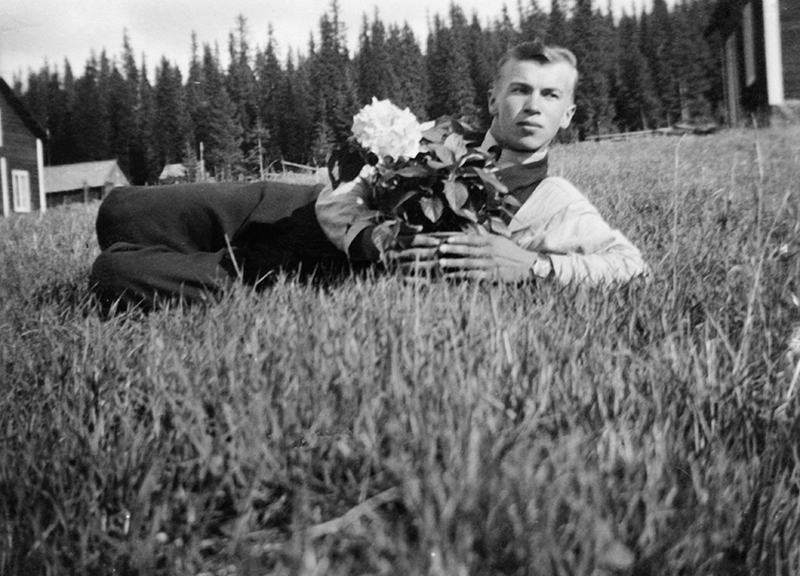 En man i gräset med en blomma.