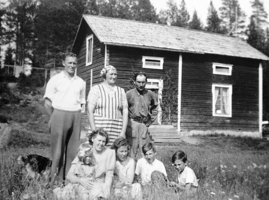 Gruppfoto utanför en stuga i Valsjönäs.
