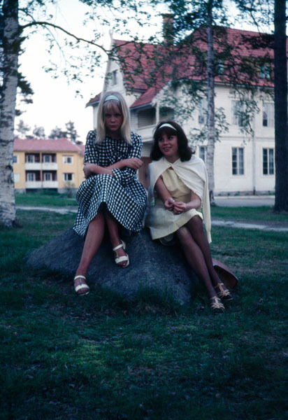 Två flickor sitter på en sten i skolparken.