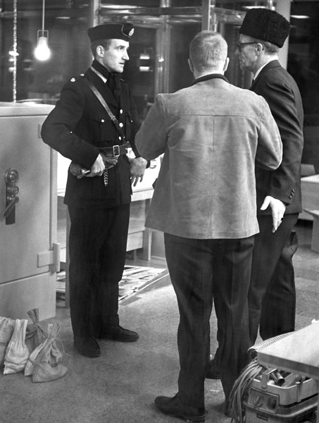 Polisman Arne Bäckman samtalar med två män.
