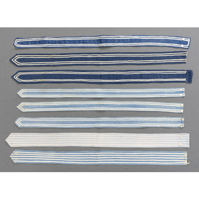 SLM 52318, 52319, 52355, 52356, 52357, 52379, 52384, 52385 - Dräkttillbehör, åtta skärp av blått tyg med påsydda vita bomullsband