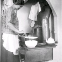 SLM M030042 - Kvinna lagar mat på en vedspis
