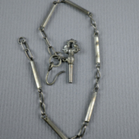 SLM 4682 - Urnyckel av silver med ornerat huvud fastsatt på kedja med stavar