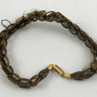 SLM 9262 3 - Armband, hårarbete flätat i öglor runt central stomme monterat i guld, tillverkat 1832