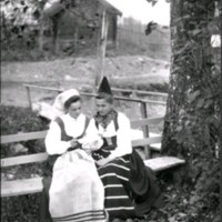 SLM Ö686 - Två folkdräktsklädda kvinnor på en bänk