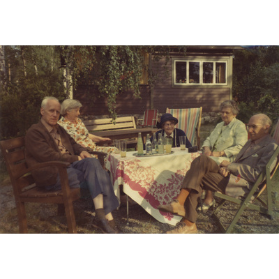 SLM P2022-1476 - Gruppfoto med makarna Höglund utanför en stuga