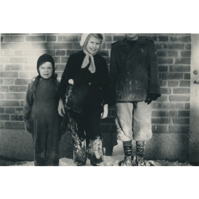 SLM P2022-1273 - Porträtt på tre barn vid en vägg