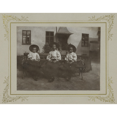 SLM P2022-0831 - Gruppbild av tre barn framför hus
