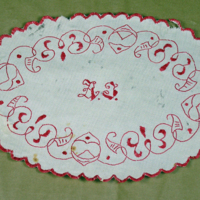 SLM 22300 - Oval duk av vit bomull, broderier i rött, bland annat monogram AF