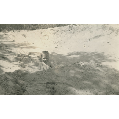 SLM P2022-1284 - Lennart halvt nedgrävd i sanden, semester 1937