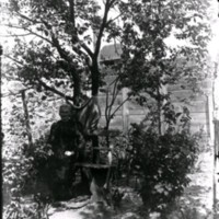 SLM Ö297 - Kvinna sitter i trädgården