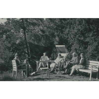 SLM P2022-1444 - Familjen Höglund sitter i utemöblerna vid skogsbrynet
