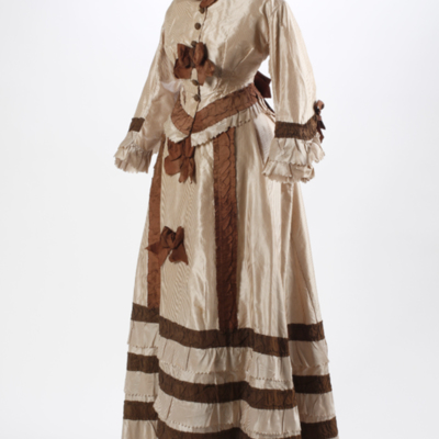 SLM 12049 - Tvådelad klänning av brunrandigt siden dekorerad med rosetter och band, 1860-tal
