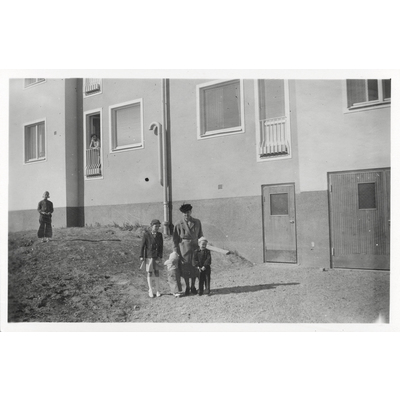 SLM P2018-0378 - Syskonen Germundson med mormor Emma utanför nya bostaden i Bollnäs i början av 1950-talet.