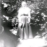 SLM Ö304 - Kvinna med halmhatt och lång kjol i trädgården