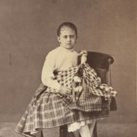 SLM P11-4228 - Ung flicka sittande på en stol med docka i knäet, 1860-70-tal