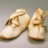 SLM 24293 - Vita babyskor av skinn med korslagda sleifar, 1920-tal