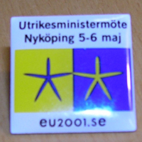 SLM 33610 1 - Pin av mässing, symbol för utrikesministermötet i Nyköping 2001