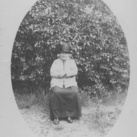 SLM P06-232 - Porträtt av sittande kvinna framför en syrénbuske