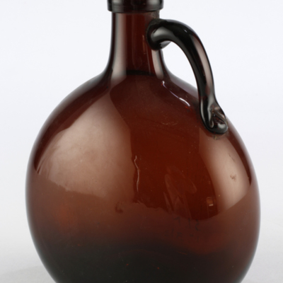 SLM 1337 - Flaska av brunt glas, rund och tillplattad, med påklippt handtag