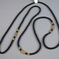 SLM 24053 - Halsband av flätade små svarta och guldfärgade pärlor, klockkedja?