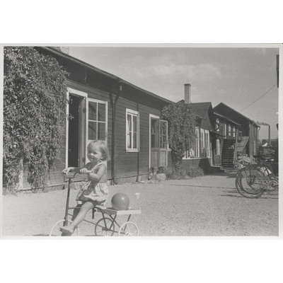 SLM P2018-0370 - Gertrud cyklar på gården, 1940-tal.