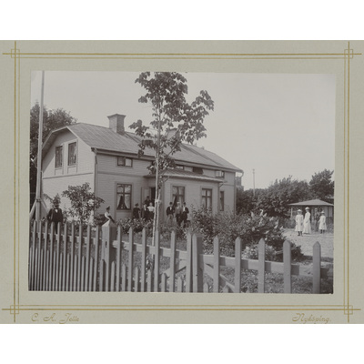 SLM P2022-0828 - Gruppfotografi i trädgård framför hus tidigt 1900-tal