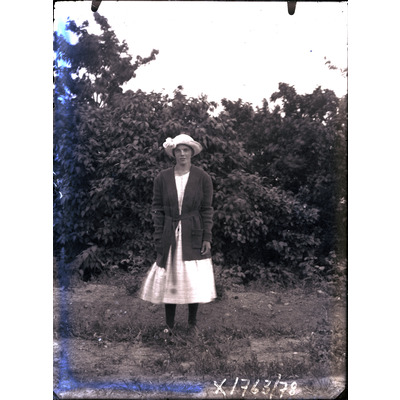 SLM X1763-78 - Flicka stående framför en syrenhäck, 1920-tal