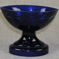 SLM 28199 - Liten båtformad skål/saltkar på rund fot, av mörkblått glas, slipad dekor