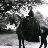 SLM M030017 - Kvinna i lång klänning på häst