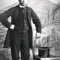 SLM M036408 - Ateljéporträtt, ung man som står vid en stol, där en hög hatt ligger