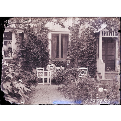 SLM X1737-78 - En man och en kvinna sitter utanför ett hus i trädgården