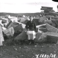 SLM X1880-78 - En kvinna sitter på en stenblock