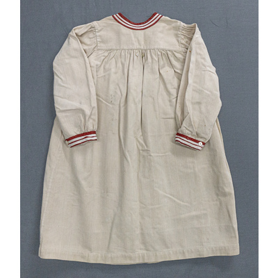 SLM 52402 - Kolt/klänning av beige bomullstyg, med röda och vita detaljer