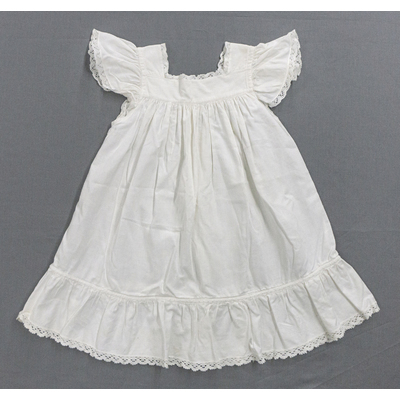 SLM 52340 - Barnförkläde av vit bomull prytt med spetsar och volanger, tidigt 1900-tal