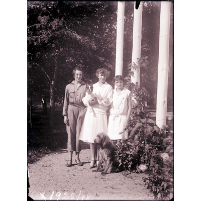 SLM X1925-78 - Tre unga kvinnor i trädgård med hundar