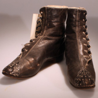 SLM 11735 - Mörkbruna knäppkängor av skinn, broderad tåhätta och vågkant längs knappraden, 1800-talets senare del