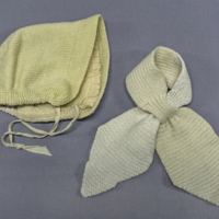 SLM 31932 19, 20 - Dockkläder, mössa och halsduk stickade av gult garn, 1950-tal