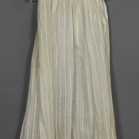 SLM 11701 - Förkläde av mönstervävd vit bomull, öppen bak, volang över axeln, ca 1900