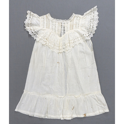 SLM 56574 - Barnförkläde av vit bomull prytt med volanger och spetsar, tidigt 1900-tal