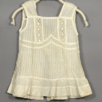 SLM 22457 - Barnförkläde av vit mönstervävd bomull med brodyrspetsar