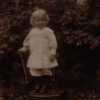 SLM P08-2199 - Liten flicka stående på en stol i trädgården