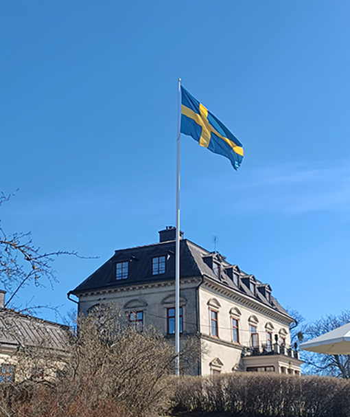 Svensk flagga hissad och vajar i vinden, i sols...