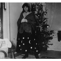 002308 - En person utklädd framför julgran.