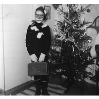 002305 - En person utklädd framför julgran.