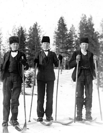 Tre okända pojkar på skidor.