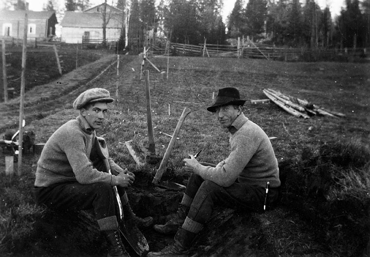 Två män vilar från dikesgrävning.