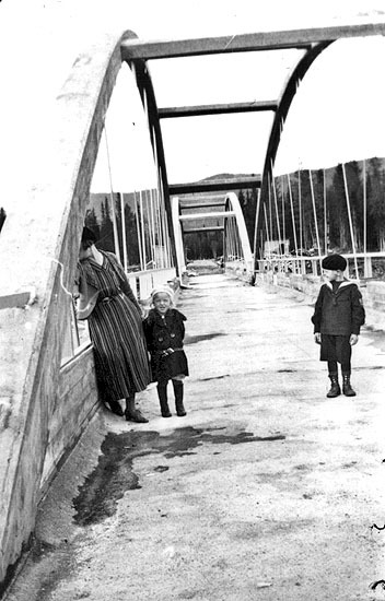 Kvinna med två barn, på en bro.