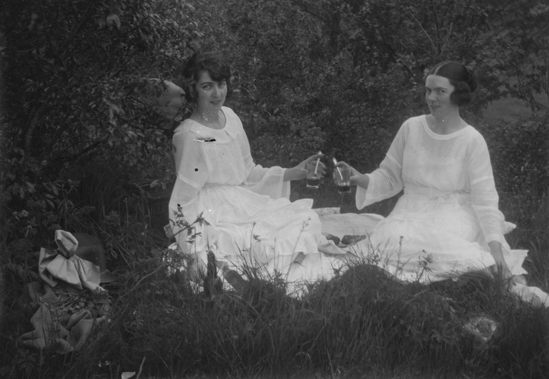 Två flickor i vitt med saftglas, sittande på ma...